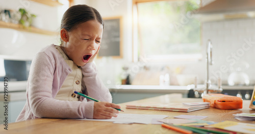 Tired, yawn and child with homework in kitchen, bored and doing project for education. Fatigue, morning or young girl with adhd yawning while drawing, learning writing or school knowledge in a house photo