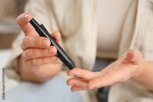 Diabetic woman using lancet pen in bedroom  closeup