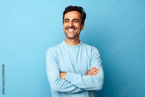 portrait of happy young man with arms crossed over blue studio background