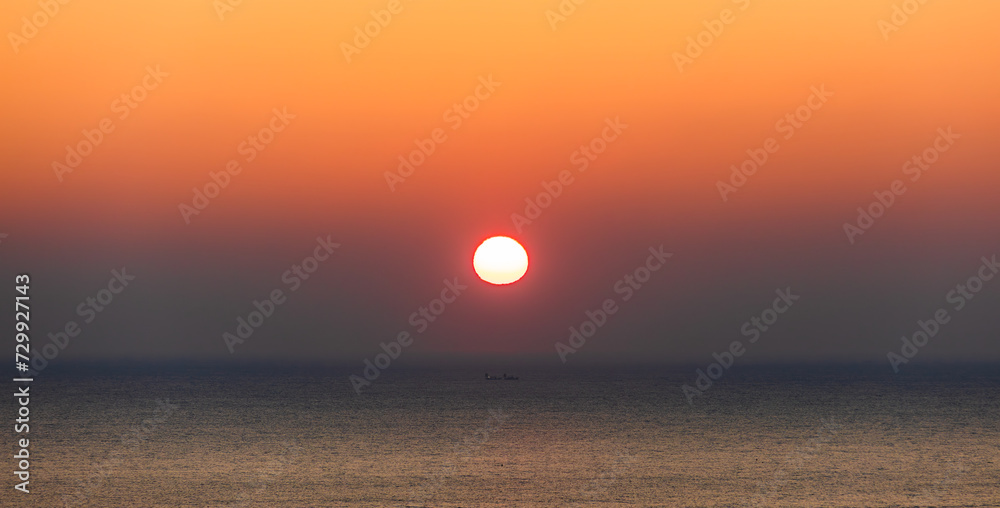 Sea sunrise landscape. Sunlight reflecting on the sea surface and a ship passing between it