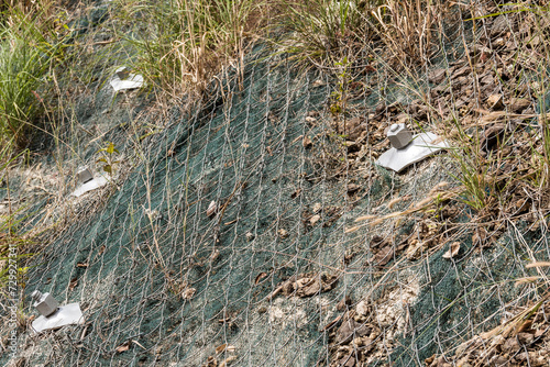 Erosion protection mesh stabilizing a sloped ground surface to prevent potential landslides along the highway. photo