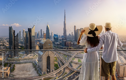 A couple on holidays enjoys the panoramic view over the city skyline of Dubai, UAE, during sunset time