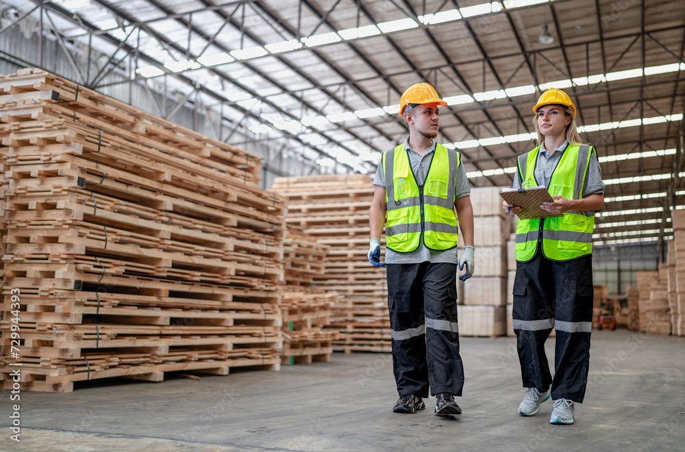 Engineer team standing walking in warehouse examining hardwood material for wood furniture production. Professional technician working on quality control in lumber plank factory. Worker check stock Engineer team standing walking in warehouse examining hardwood material for wood furniture production. Professional technician working on quality control in lumber plank factory. Worker check stock