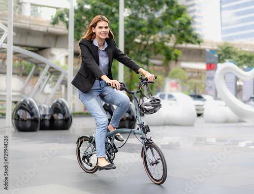 Eco friendly, businesswoman ride bicycle outside to reduce carbon footprint. Environmental preservation woman riding bike in downtown. Cycling, alternative energy transportation for climate change.