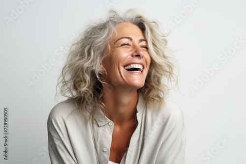 Portrait of a happy senior woman laughing on a gray background.
