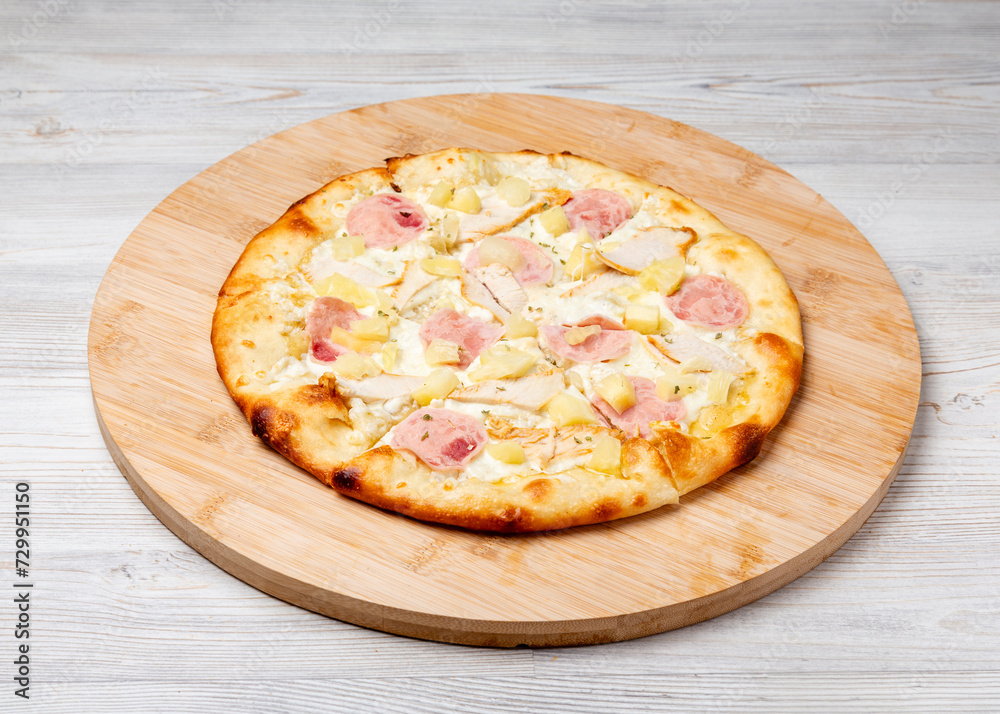Italian Hawaiian pizza with ham and pineapples on a wooden board Italian Hawaiian pizza with ham and pineapples on a wooden board