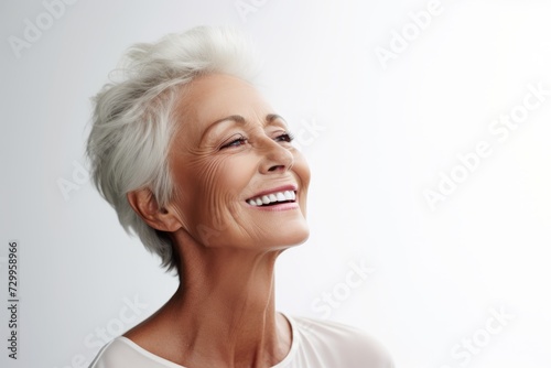 Mature beauty. Close up of beautiful mature woman smiling and looking away while standing against grey background