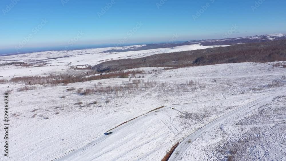 Aerial view of a car driving on a winter road. Winter countryside landscape Aerial view of a car driving on a winter road. Winter countryside landscape