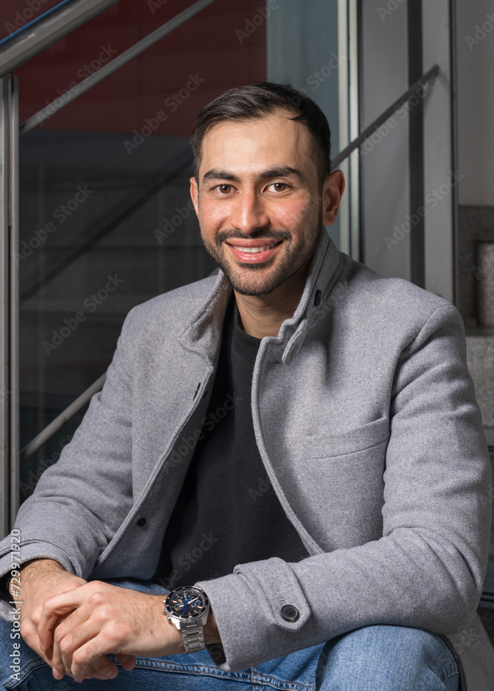 Portrait of a handsome young man. Smiling Asian man with a neat beard stands near a wall and looks at the camera Portrait of a handsome young man. Smiling Asian man with a neat beard stands near a wall and looks at the camera