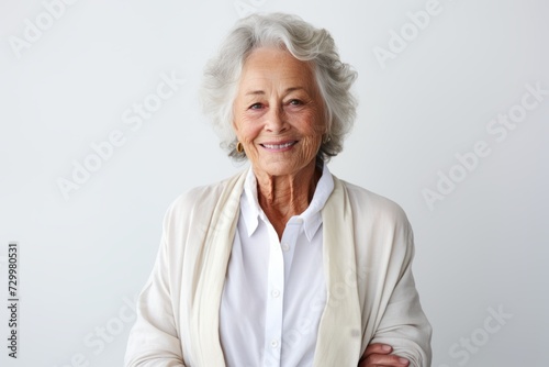 Portrait of smiling senior woman looking at camera and standing against grey background