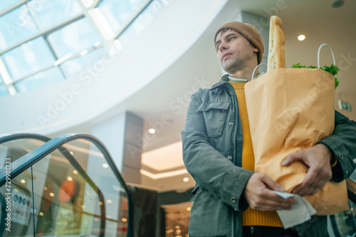 Canvastavla Man holds paper bag filled with various food items in his hand in mall