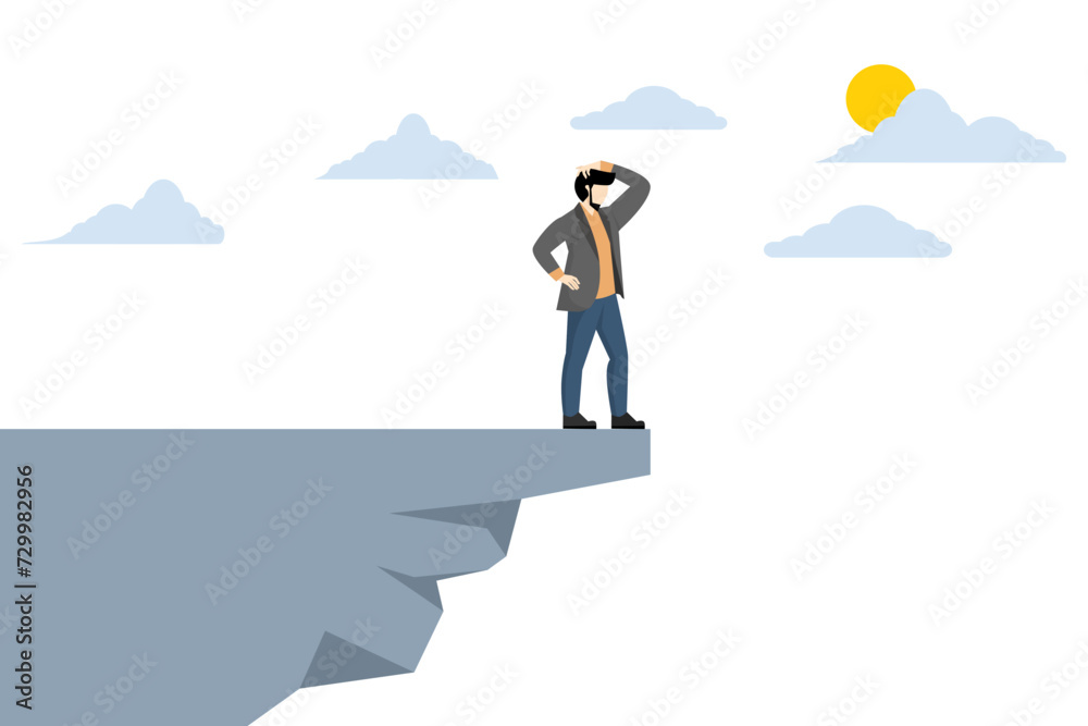 Investment risk or financial fallout due to economic recession, fear of losing money or paying back debt, businessman standing on the edge of a cliff in the sky looking down because of fear of heights Investment risk or financial fallout due to economic recession, fear of losing money or paying back debt, businessman standing on the edge of a cliff in the sky looking down because of fear of heights