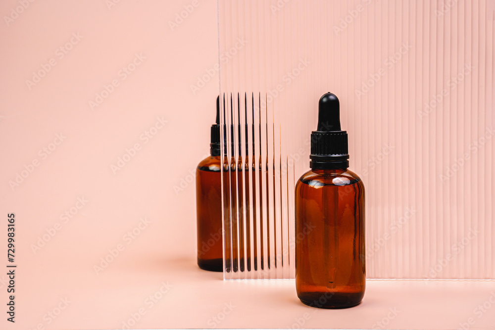 Hair oil is behind glass. Massage oil on a pink background. A bottle of cosmetics.