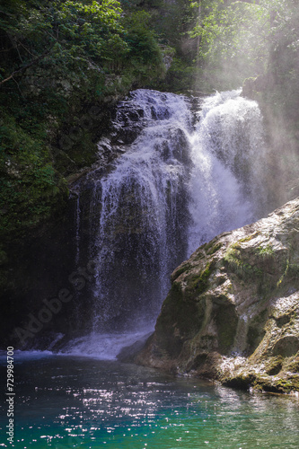 turquoise crystal clear water of a waterfall of a mountain Alpine river