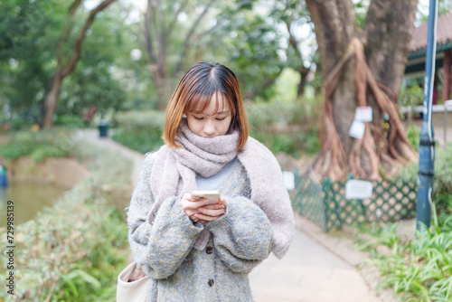 冬の寒い香港尖沙咀の公園で過ごす20代の中国人女性 A Chinese woman in her 20s spending time in a park in Tsim Sha Tsui, Hong Kong, which is cold in winter photo