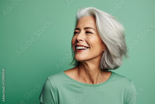 Portrait of happy mature woman with white hair on green background.