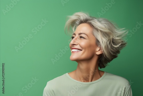 smiling middle aged woman looking up on green background with empty copy space