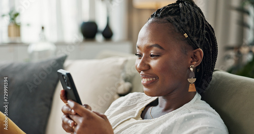 Funny, smile and black woman on a couch, cellphone or connection with social media, comedy post or laugh. African person, apartment or girl on sofa, smartphone or mobile user with humor, home or joke photo
