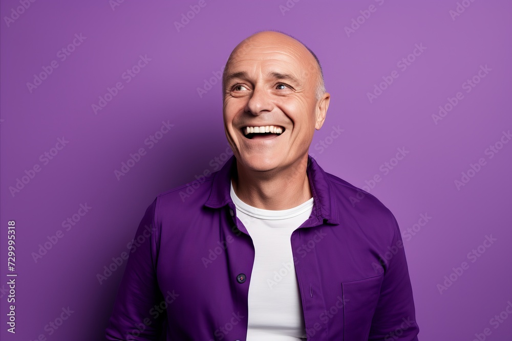 Portrait of a happy senior man laughing and looking at camera against purple background Portrait of a happy senior man laughing and looking at camera against purple background