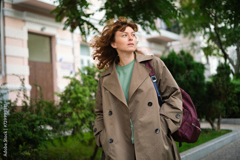 Portrait of happy mature woman looking at camera. Successful proud woman in city street at sunset. Satisfied Caucasian woman in formal clothing smiling outdoors. High quality photo