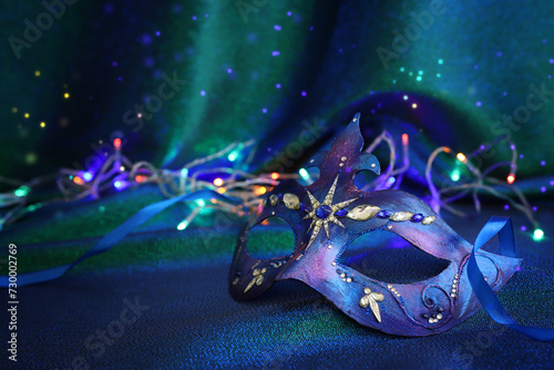 Photo of elegant and delicate Venetian mask over blue and green dark background