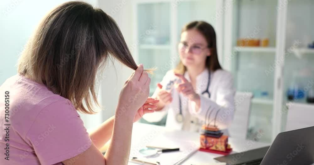 Doctor offers cure for split ends to female patient in clinic. Pharmacological products for hair restoration Doctor offers cure for split ends to female patient in clinic. Pharmacological products for hair restoration