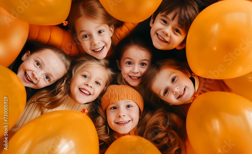 Children smiling, lying with balloons at a birthday party. A group of children are playing, frolicking with balloons, having fun. Orange-brown tones. Concept of children's holiday, fun. Flat lay