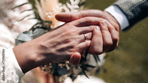 Young married couple holding hands, ceremony wedding day. Groom holding bride's hand, close up photo