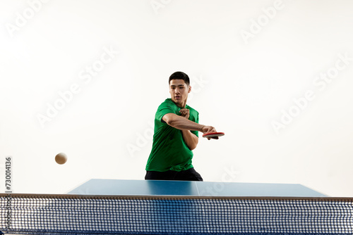 Athletic table tennis stance from competitive Asian sportsman, player in sportswear in motion against white studio background. Concept of sport, hobby, lifestyle, match, victory, championship. photo