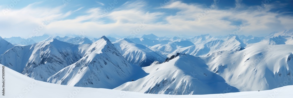 Landscape of a winter mountain range covered in snow with a bright blue sky.