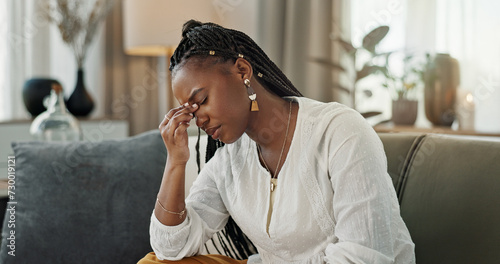 Headache, burnout and young black woman in the living room of her modern apartment on weekend. Stress, mental health and sick African female person with migraine for illness in lounge at home. photo