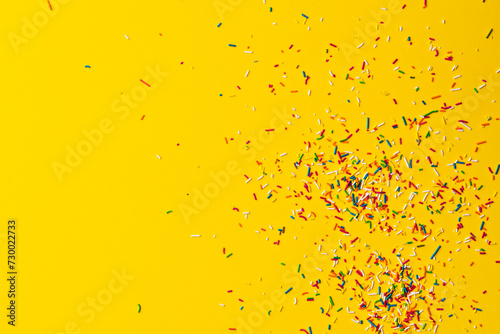 Colourful cake sprinkles on yellow background © belekekin