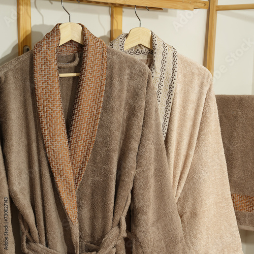 Bathrobe set - Hanger with clean bathrobe and towel on light wall bathrobe mockup