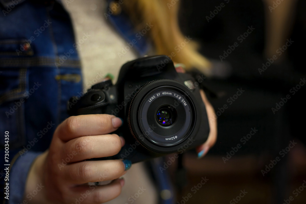 The girl holds a black camera in her hand