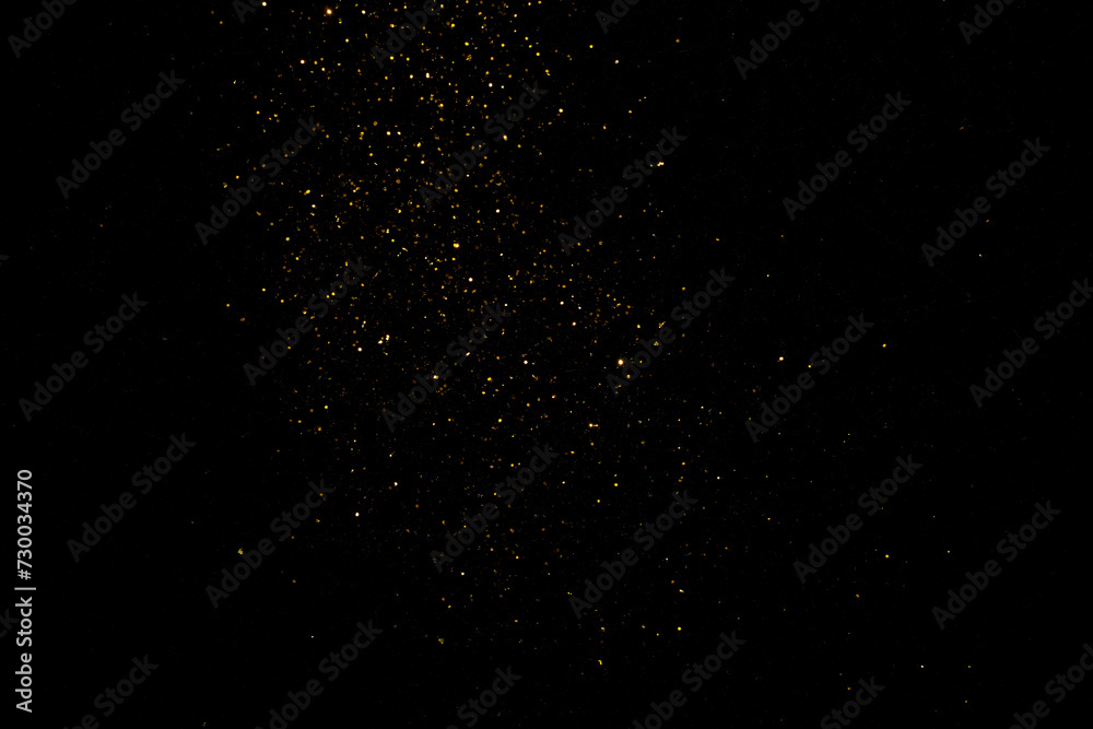 Obraz premium group of small golden flakes are scattered on the black surface
