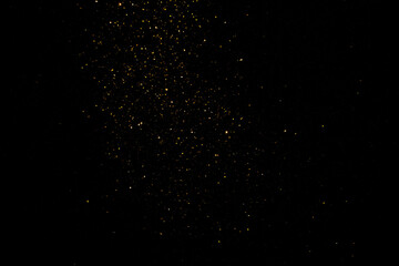 group of small golden flakes are scattered on the black surface