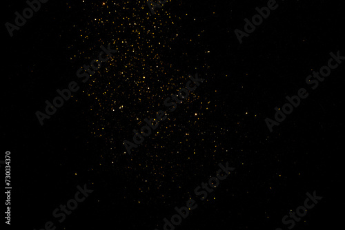 group of small golden flakes are scattered on the black surface