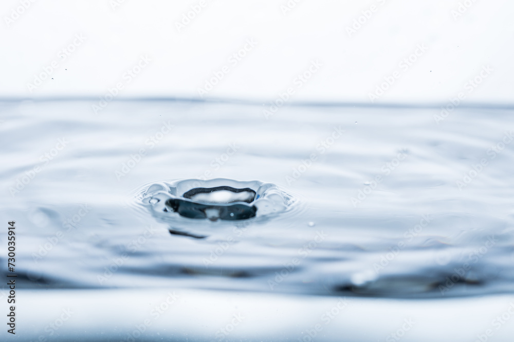 Small water splash against a pristine white backdrop. Perfect for illustrating freshness or adding dynamic energy to a minimalist composition. Ideal for advertising or conceptual designs.