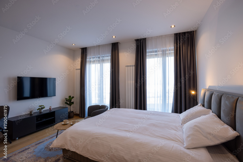 Interior of a bedroom with large master bed and wall mouted tv