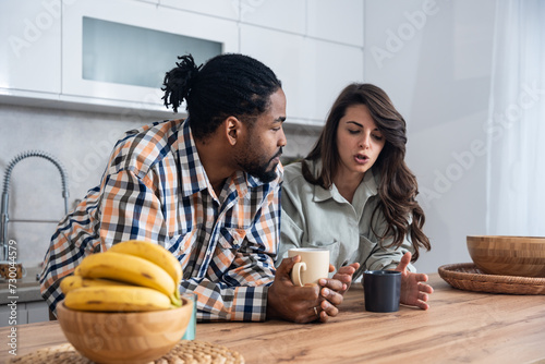 Simple living. Young couple drinking their first morning coffee in the kitchen discussing improving the quality of their love relationship, respect they have for each other and their plans for the day photo