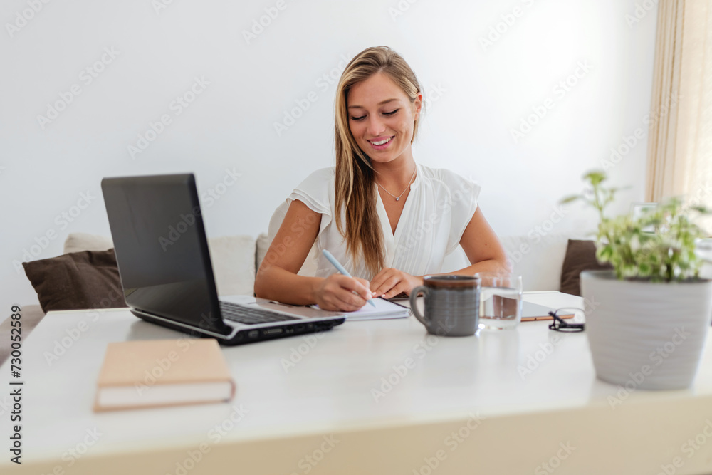 Cropped shot of an attractive young businesswoman writing in her notebook while working in her home office. Cropped shot of an attractive young businesswoman writing in her notebook while working in her home office.