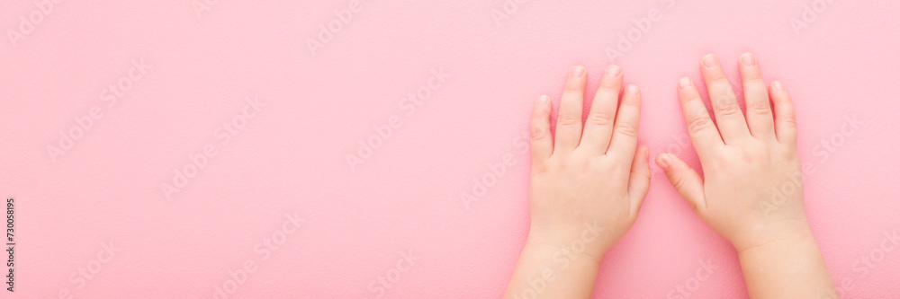 Little girl hands on light pink table background. Pastel color. Closeup. Point of view shot. Wide banner. Empty place for text. Top down view.