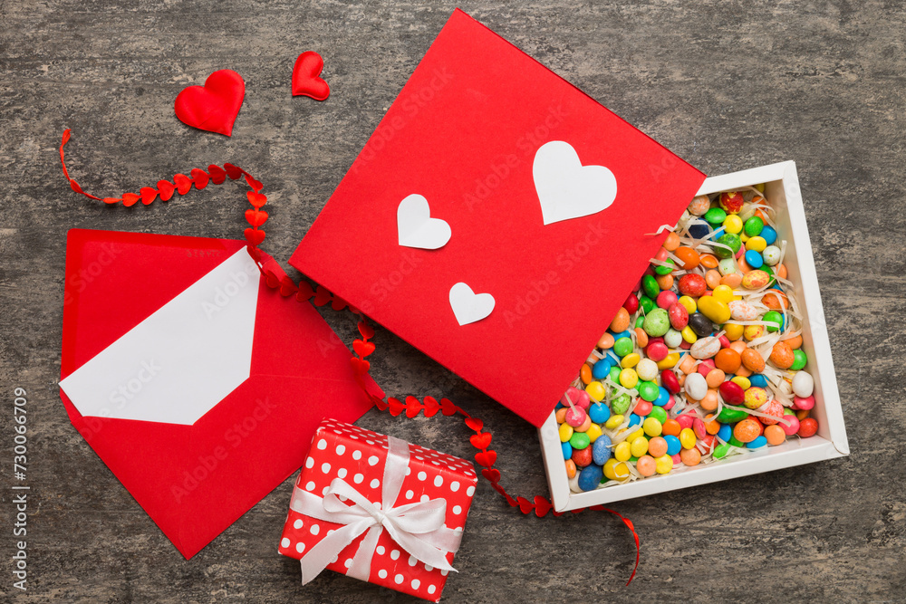 Red envelope with candy and gift box and Valentines hearts on colored background. Flat lay, top view. Romantic love letter for Holiday concept Red envelope with candy and gift box and Valentines hearts on colored background. Flat lay, top view. Romantic love letter for Holiday concept