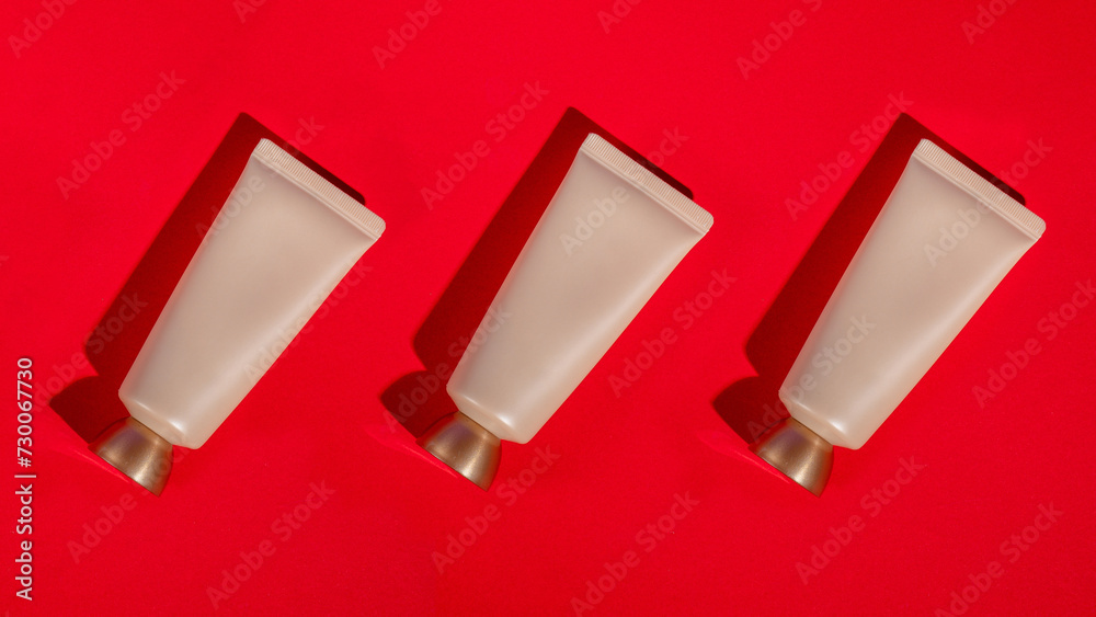 Plastic white tube for cream or lotion. Skin care or sunscreen cosmetic on red background. Plastic white tube for cream or lotion. Skin care or sunscreen cosmetic on red background.
