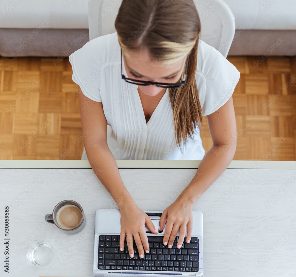 Woman with laptop, notes and typing in home office planning freelance ...