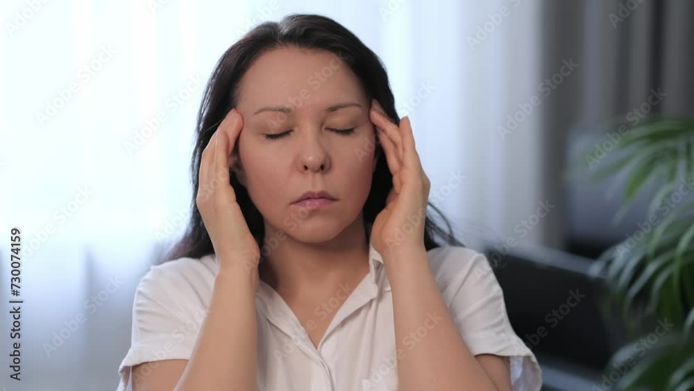 Woman with closed eyes, pressing temples in a gesture of stress relief or headache pain. Suitable for health and wellness publications. Woman with closed eyes, pressing temples in a gesture of stress relief or headache pain. Suitable for health and wellness publications.