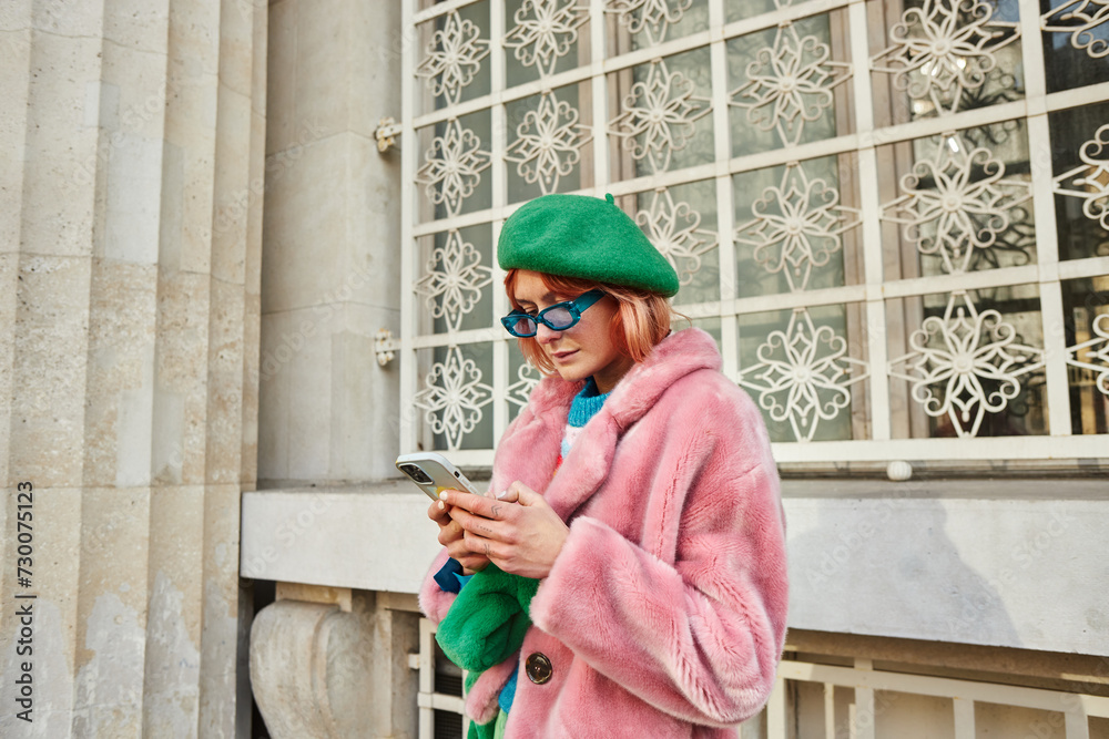 woman in sunglasses and trendy faux fur jacket using smartphone on street in Vienna, Austria