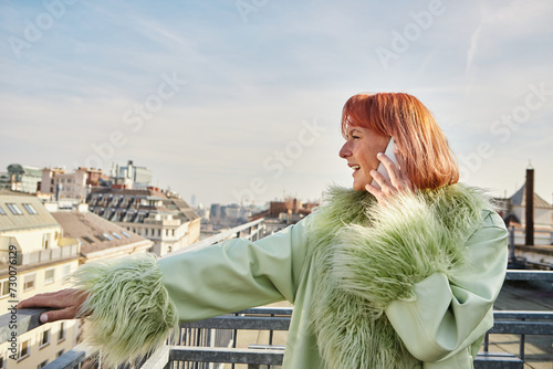 Photography trendy woman in stylish casual attire talking on mobile phone on roof terrace in
