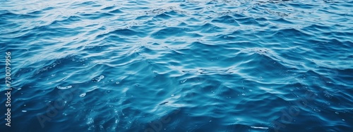 A close-up of gentle waves rippling on the surface of the blue sea. It is intended to be used as a banner.