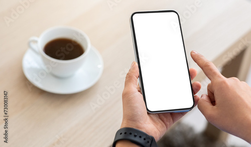 Cropped of woman scrolling on smartphone while drinking coffee